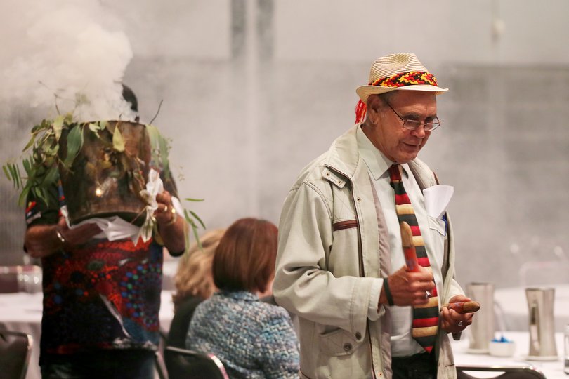 Elder performing a traditional smoking ceremony with smouldering eucalyptus leaves